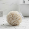 SWEETBODZ Bath Pouf Loofah resting on a tiled bathroom surface beside a bath
